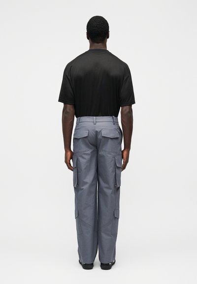 Μαύρο κοντομάνικο μπλουζάκι και γκρι cargo παντελόνι με τσέπες, ίσια μπατζάκια και ελαφρώς υφή. Κατάλληλο για καθημερινή χρήση.