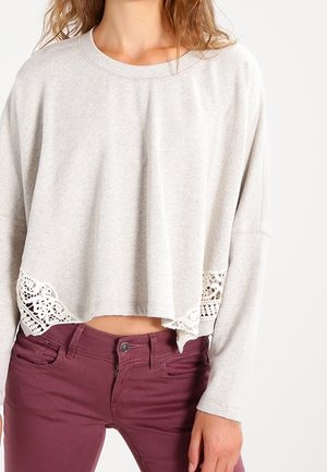 Helles graues, kurz geschnittenes Sweatshirt mit Spitzenakzenten am Saum, mit langen Ärmeln und rundem Ausschnitt, kombiniert mit burgunderfarbenen Hosen.