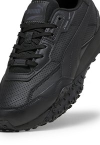 Baskets Puma noires avec semelle texturée, tige en cuir perforé, lacets noirs, et logo Puma visible sur la languette et le côté.
