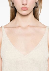 Top in maglia beige con scollo a V e spalline sottili, caratterizzato da un tessuto texturizzato. Dettaglio ravvicinato della scollatura e dell'area delle spalle.