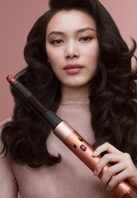 Locktång med svart fat och roséguldselement, utrustad med knappar för temperaturreglering. Greppet är texturerat för bättre hantering.