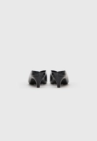 Schwarze Leder-Absatzschuhe mit spitzer Zehenpartie, ausgestattet mit einem niedrigen, stabilen Absatz und einem offenen Rückendesign. Glatte Textur und minimalistische Details.