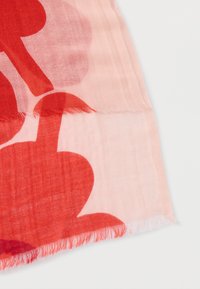 Punase ja roosa sall, millel on abstraktsed kujundid, valmistatud kergest kangast. Servad on narmendatud, et lisada tekstuurne viimistlus.