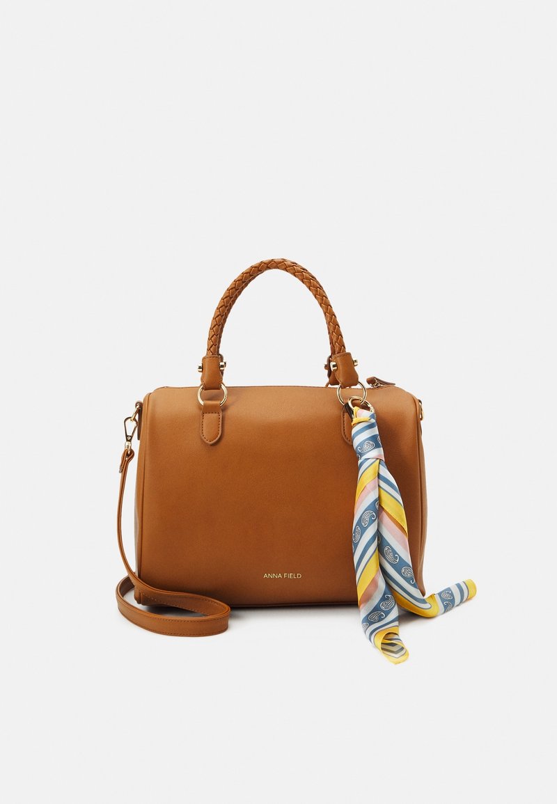 Braune Ledertasche mit geflochtenen Griffen, abnehmbarem Schulterriemen und einem gemusterten Schal in Blau, Gelb und Rosa als Akzent.