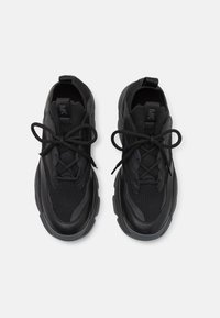 Black athletic shoes with a mesh upper, textured details, padded collar, and laces. Rounded rubber soles with traction patterns.