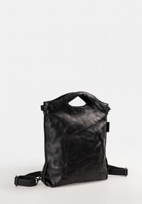 Zwarte leren rugzak met een gestructureerde vorm, voorzien van een bovenhandvat en verstelbare schouderbanden. Gladde textuur met minimale detaillering.