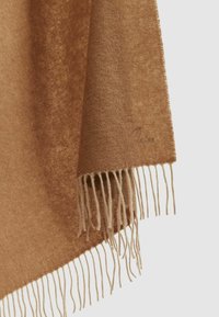 Brun cashmere tæppe med blød tekstur, der har frynser i kanten og en subtil glans. Broderet logo nær frynserne.