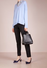 Ljusblå oversized v-ringad tröja, svarta tajta byxor, marinblå slingback-klackar med rosetter och en liten svart läderhandväska.