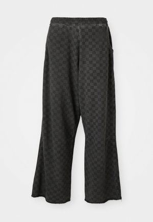 Schwarz-weiße karierte Hose mit elastischem Bund, lockerer Passform, seitlichen Taschen und rohen Saumdetails. Hergestellt aus weichem Stoff mit einer strukturierten Oberfläche.