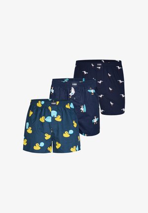 Tre par mørkeblå boxershorts med legende tryk: gule gummiænder med bobler, måger med surfbrætter og almindelige måger.