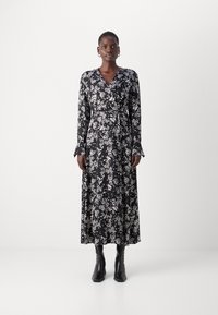 Crna cvjetna haljina s wrap krojem koja ima duge rukave, strukiranu sredinu i lepršavu siluetu. Okićena bijelim botaničkim uzorcima i proširenim manžetama.