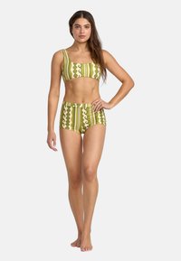 Green and cream patterned bikini set with a square neckline and high-waisted bottoms, featuring vertical stripes and wavy accents.