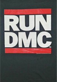 Svart t-skjorte med "RUN DMC" i stor hvit skrift, med en rød rektangulær akzent over og under teksten.