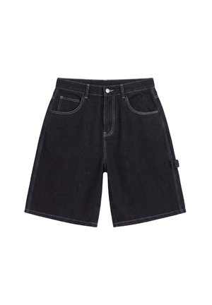 Jeune homme portant une chemise rouge à fleurs à manches courtes par-dessus un t-shirt blanc à motif, un short long noir, des baskets blanches et des chaussettes blanches avec des logos.