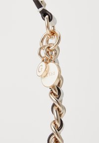 Gold-tone chain bracelet featuring interwoven black and white leather accents. Includes round logo charms with "G" and "GUESS" engravings.