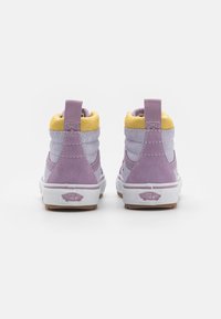 Baskets montantes en suède violet avec des accents jaunes, des panneaux texturés et une semelle en caoutchouc blanche. L'arrière présente une languette pour un enfilage facile.