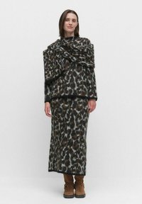 Stickad djurmönstrad outfit som består av en lös topp och en figurnära kjol. Färgschemat inkluderar brunt, svart och grått. Mjuk, texturerad textil.