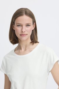 Balts, īsām piedurknēm T-krekls ar apaļu kakla izgriezumu, izgatavots no mīkstas auduma. Vienkāršs dizains bez rakstiem vai aprīkojuma detaļām.