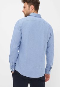 Blauw geruit overhemd met lange mouwen en knopenmanchetten. Bevat een klassieke kraag en een licht gebogen zoom. De stof lijkt glad en licht van gewicht.