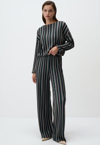 Gestreepte jumpsuit in donkergroen, met lange mouwen, een bootnek en wijde pijpen met verschillende gekleurde strepen.