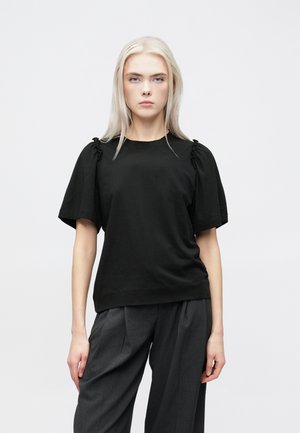 Top preto de manga curta com detalhes franzidos nos ombros, feito de tecido suave. Combinado com calças largas cinzas, exibido contra um fundo branco.