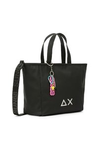 Borsa a mano nera con doppio manico, dotata di chiusura zip, materiale simile alla gomma, logo geometrico bianco e un charm colorato attaccato.
