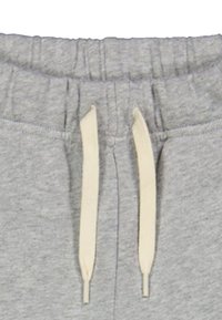 Grijze sweatpants hebben een elastische tailleband met een crèmekleurige trekkkoord, met aan de zijkanten twee zakken en een zachte, textuurstof.