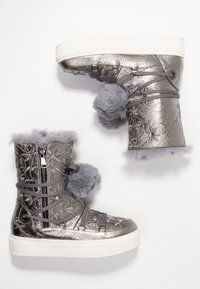 Bottes d'hiver en métal argenté avec des motifs floraux, fermeture éclair latérale, pompons gris, doublure en fourrure et semelles épaisses en caoutchouc blanc.