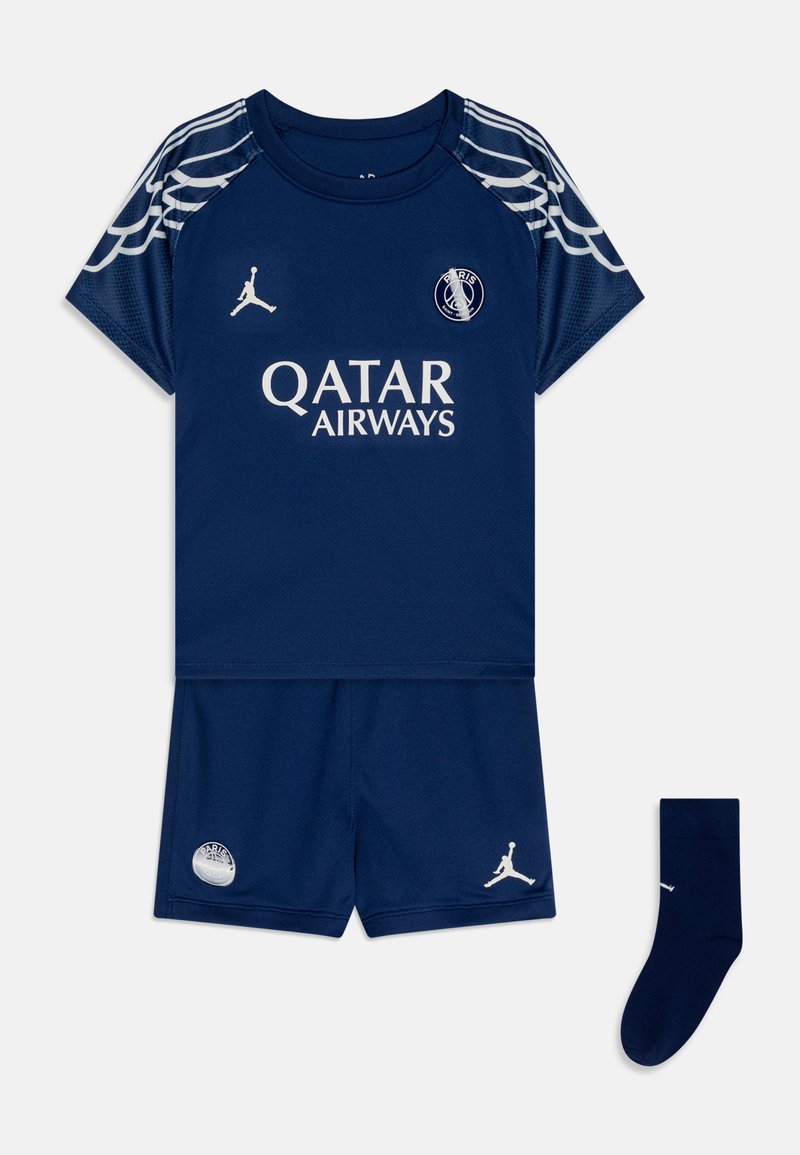 Mørkeblå sport antrekk inkludert en kortermet skjorte med hvit logo og vingedetaljer, matchende shorts og en liten blå sokk.