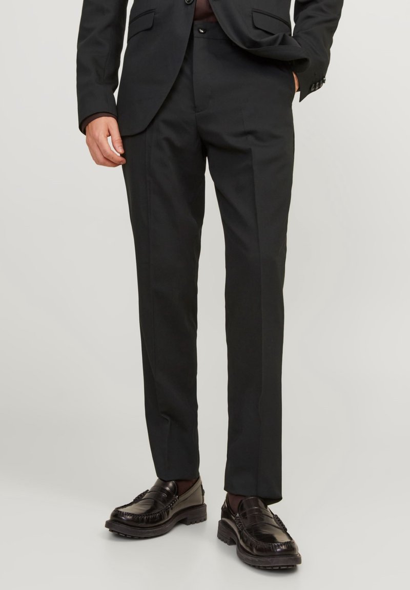 Musta dress-pants, valmistettu sileästä kankaasta, slim fit -tyylillä, jossa on sivutaskut ja litteä etupuoli, yhdistettynä tummiin kenkiin.