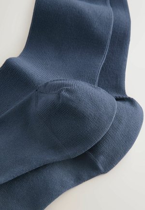 Navy blue crew socks made of textured knit fabric, featuring reinforced toe and heel areas for durability and comfort.