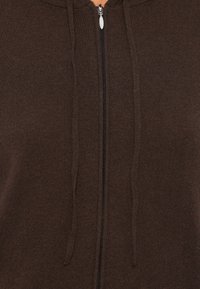 Bruine ritsachtige hoodie met ribbelstructuur, voorzien van een rits aan de voorkant en koordjes aan de capuchon. Soepele stof met een casual ontwerp.