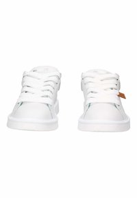 Zapatillas blancas con material sintético suave, cordones planos, logo en la lengüeta y una etiqueta de acento marrón cerca del talón. Diseño de perfil bajo y suela de goma.