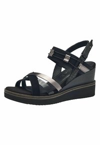 Sandales à talons compensés noires, composées d'un mélange de daim et de matériaux synthétiques, avec des brides métalliques et un talon texturé.