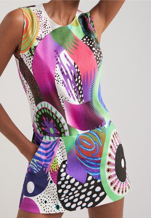 Robe sans manches avec des motifs abstraits éclatants en violet, vert, bleu, noir et blanc sur le torse et les parties supérieures des jambes d’un modèle.