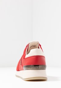 Baskets en cuir synthétique rouge avec accents blancs, panneau texturé, col rembourré et logo métallique "MICHAEL KORS" sur le talon.