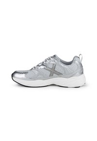 Zapatilla deportiva plateada con una superficie texturizada, diseño perforado y suela de goma blanca. Presenta una suela negra contrastante y cordones negros.