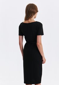 Black, form-fitting dress with short sleeves and a slight V-neck, featuring a waistband and a back zipper detail. Smooth texture.