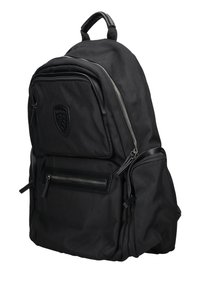 Zaino in nylon nero con tasche con zip, spallacci imbottiti e una patch con logo. Presenta una superficie testurizzata e dettagli in pelle.