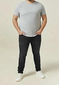 Grå kortärmad t-shirt som bärs med svarta slim-fit jeans och vita sneakers. T-shirten har en rundad halsringning och en mjuk textur.