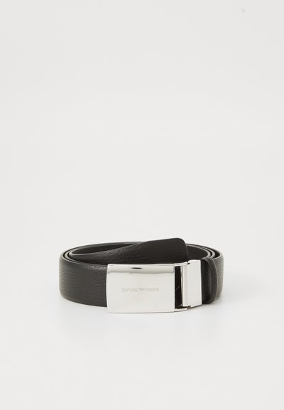 Cintura in pelle nera arrotolata con fibbia argentata lucida incisa "Emporio Armani" su sfondo bianco semplice.