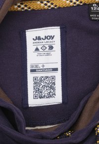 Marine stoffen label met een wit etiket waarop zwarte tekst, een QR-code en ontwerpelementen staan. Accentuated met een geweven gele en marineblauwe rand.