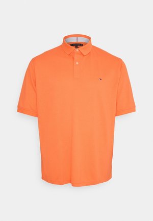 Polo arancione in morbido tessuto di cotone traspirante. Presenta una patta con tre bottoni e un piccolo logo sul petto. Vestibilità classica.