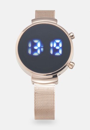 Relógio digital com caixa redonda na tonalidade dourada, fundo preto e ecrã LED azul a mostrar a hora 13:19. Apresenta uma bracelete de metal em malha.