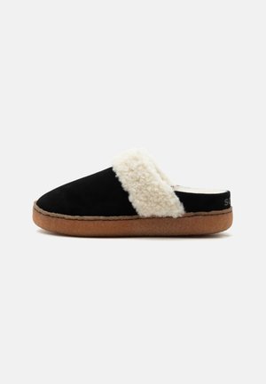 Chausson noir à enfiler avec doublure duveteuse couleur crème et semelle marron, conçu pour le confort intérieur.