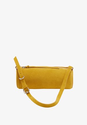 Musztardowo-żółta zamszowa cylindryczna torba na ramię z regulowanym paskiem i górnym zamkiem błyskawicznym na białym tle.