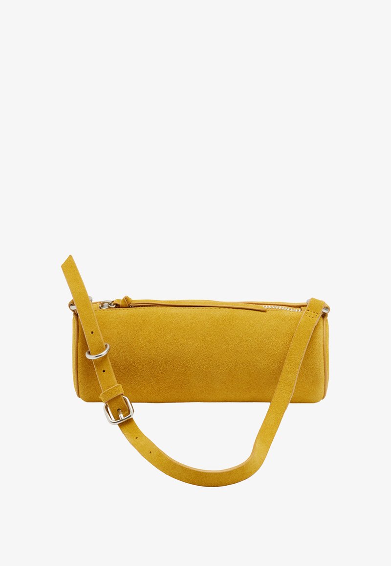 Musztardowo-żółta zamszowa cylindryczna torba na ramię z regulowanym paskiem i górnym zamkiem błyskawicznym na białym tle.