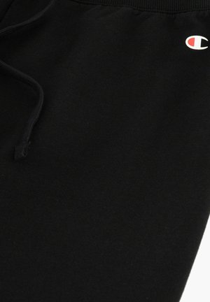 Joggers de algodón negro con cintura elástica, cordón y un pequeño logo blanco y rojo en la parte inferior de la pierna. Textura suave.