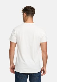 Weißes T-Shirt mit kurzen Ärmeln, Rundhalsausschnitt und geradem Saum. Der Stoff wirkt glatt und wird mit blauen Jeans kombiniert.
