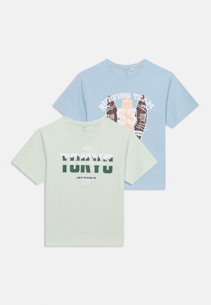 Zwei T-Shirts mit kurzen Ärmeln und Rundhalsausschnitt, eines hellgrün mit dem Schriftzug "TOKYO" und eines hellblau mit Surf-Grafik und dem Schriftzug "Surfing Team".